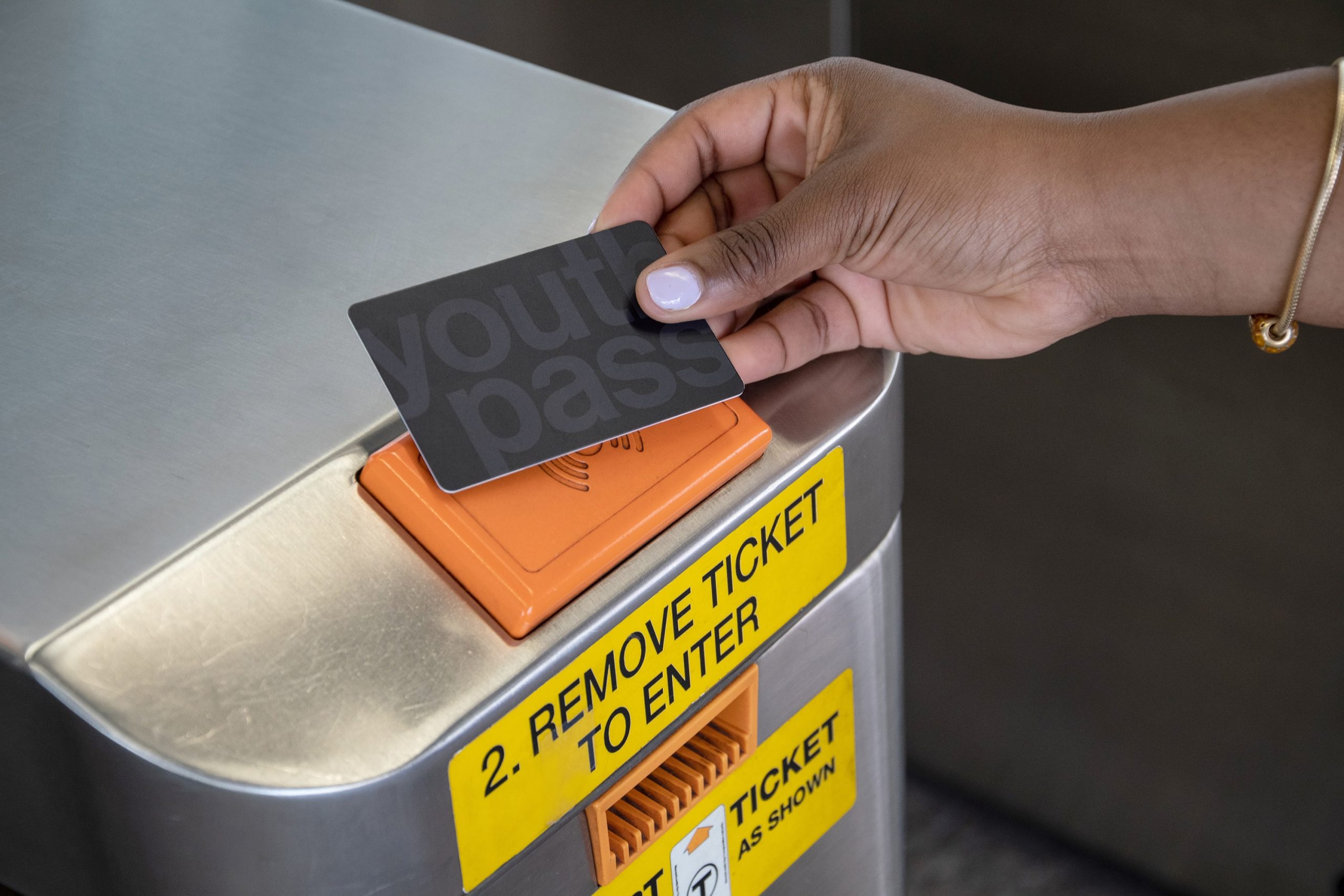 A hand holds a Youth Pass card to a card reader